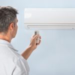 Man Operating Air Conditioner With Remote Controller